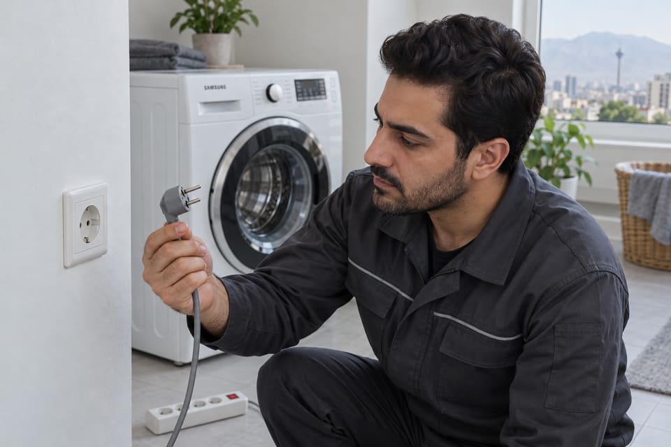 دست در حال بررسی دوشاخه جداشده لباسشویی کنار پریز دیواری، با چندراهی کنار گذاشته شده